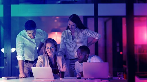 Colleagues gathered around two laptops